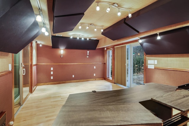 workout area with lofted ceiling, rail lighting, and light wood-type flooring