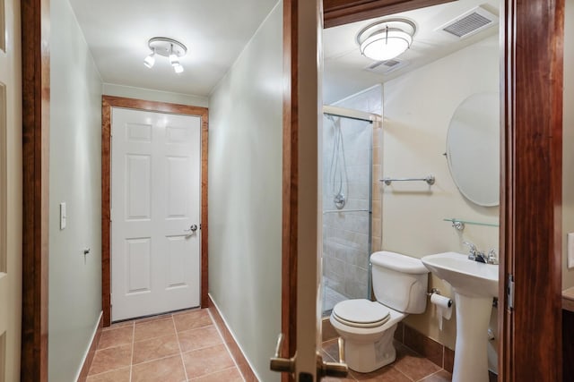 bathroom featuring sink, toilet, a shower with shower door, and tile patterned flooring