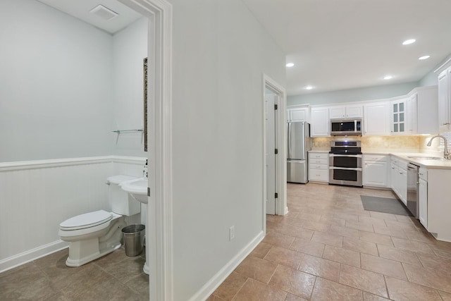 kitchen featuring stainless steel appliances, white cabinetry, sink, and decorative backsplash