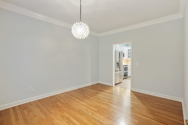 spare room with an inviting chandelier, ornamental molding, and light hardwood / wood-style floors