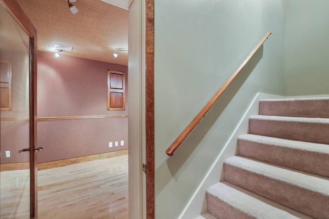 stairway with hardwood / wood-style floors and a textured ceiling