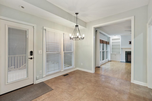 unfurnished dining area featuring built in shelves and a chandelier