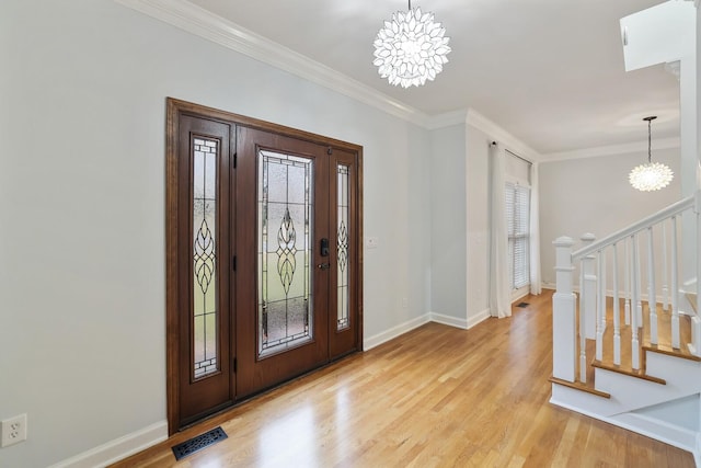 entrance foyer with ornamental molding, a chandelier, and light hardwood / wood-style flooring