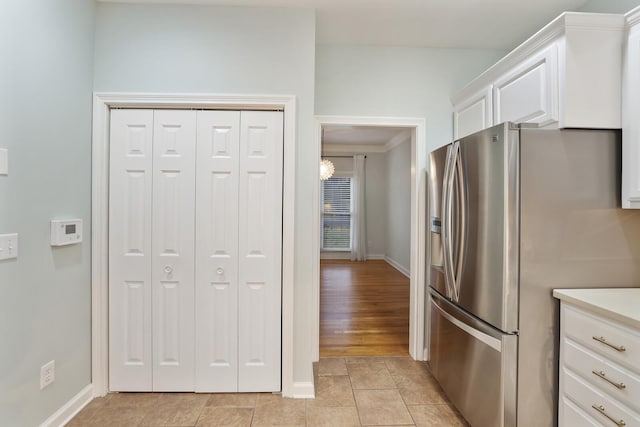 kitchen featuring stainless steel refrigerator with ice dispenser, light tile patterned floors, and white cabinets