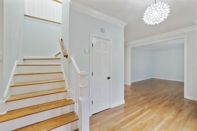 stairway with ornamental molding and hardwood / wood-style floors