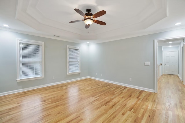 empty room with ornamental molding, light hardwood / wood-style floors, a raised ceiling, and ceiling fan