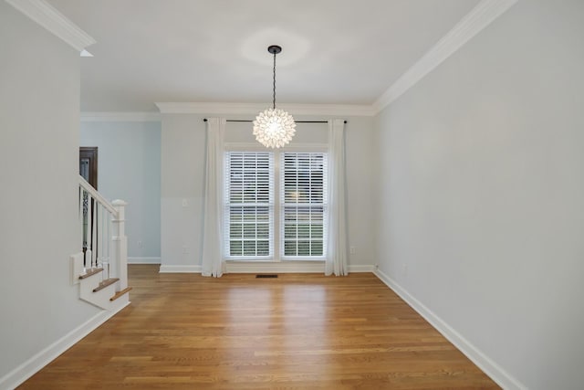 unfurnished dining area with wood-type flooring, ornamental molding, and a chandelier