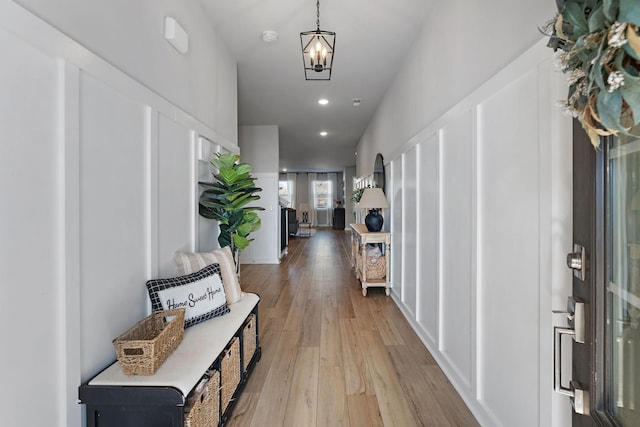 hallway with an inviting chandelier and light hardwood / wood-style flooring