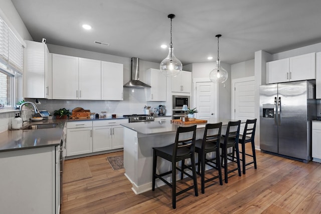 kitchen with stainless steel appliances, sink, white cabinets, and wall chimney exhaust hood