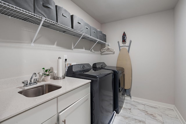 washroom featuring a sink, baseboards, marble finish floor, cabinet space, and washing machine and clothes dryer