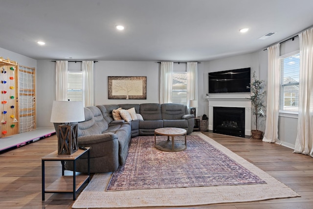 living room featuring a fireplace, recessed lighting, visible vents, light wood-style floors, and baseboards