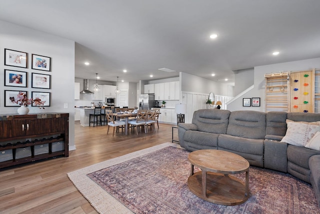 living room featuring stairs, light wood-style flooring, and recessed lighting