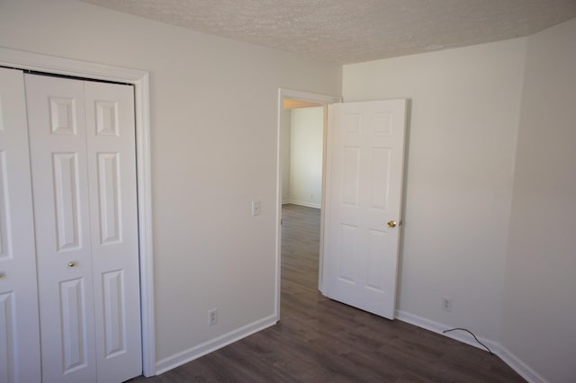 unfurnished bedroom with dark hardwood / wood-style floors, a textured ceiling, and a closet