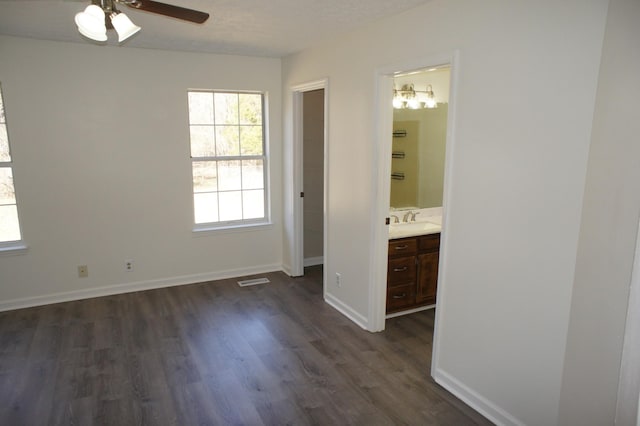 unfurnished bedroom featuring sink, dark wood-type flooring, a textured ceiling, and ensuite bathroom