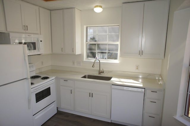 kitchen with white cabinetry, sink, dark hardwood / wood-style flooring, light stone countertops, and white appliances