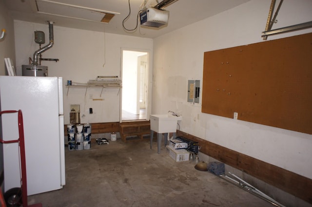 garage featuring white refrigerator, a garage door opener, electric panel, and water heater