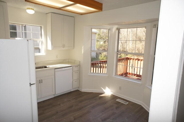 kitchen with white cabinetry, dark hardwood / wood-style flooring, sink, and white appliances