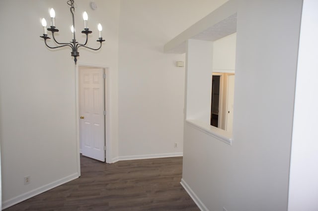 corridor with an inviting chandelier and dark hardwood / wood-style flooring