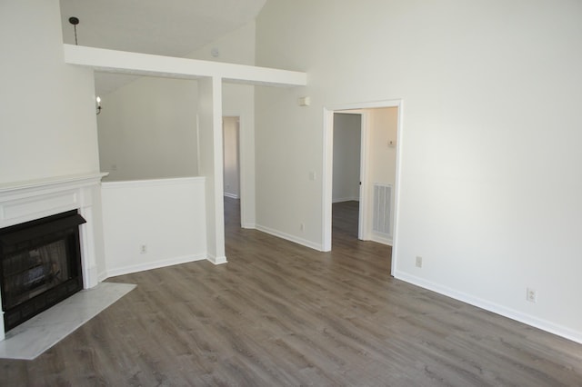 unfurnished living room with dark wood-type flooring and high vaulted ceiling