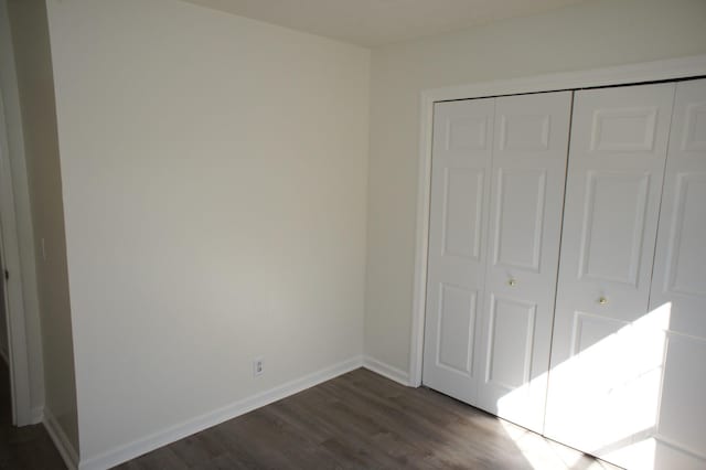 unfurnished bedroom featuring dark hardwood / wood-style flooring and a closet