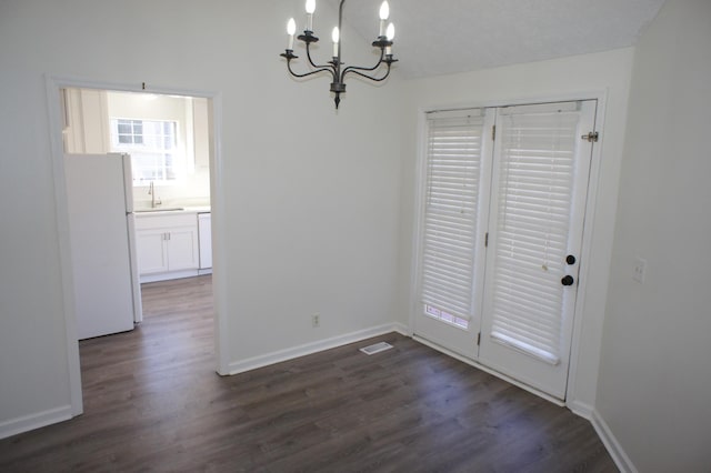 unfurnished dining area with dark hardwood / wood-style flooring, sink, and an inviting chandelier