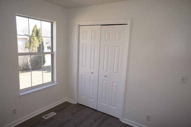 unfurnished bedroom with a closet and dark hardwood / wood-style floors