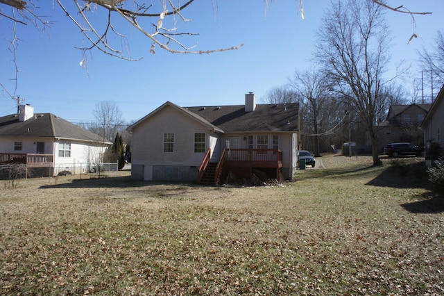 back of property with a deck and a lawn