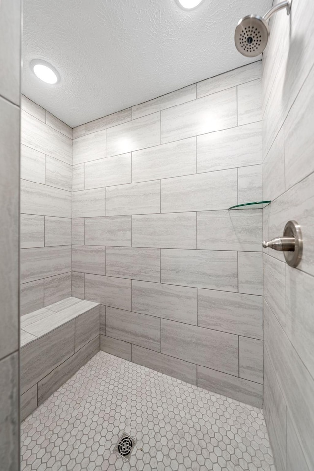 bathroom with a tile shower and a textured ceiling