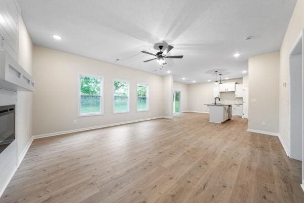 unfurnished living room with light hardwood / wood-style floors and ceiling fan