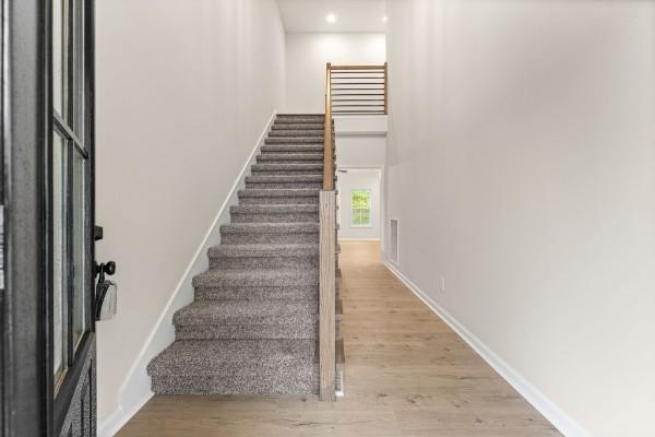 staircase with hardwood / wood-style floors and a high ceiling