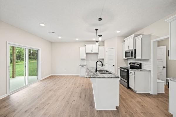 kitchen with appliances with stainless steel finishes, decorative light fixtures, sink, and dark stone counters