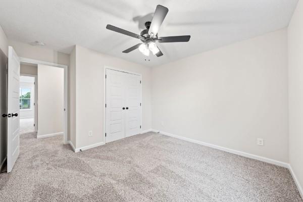 unfurnished bedroom with light carpet, ceiling fan, and a closet