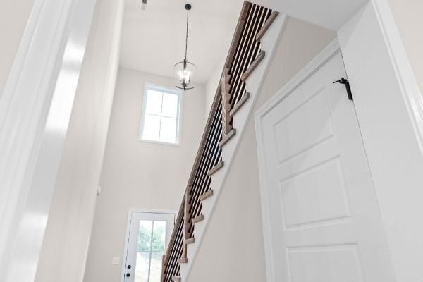 staircase with a wealth of natural light, a chandelier, and a high ceiling