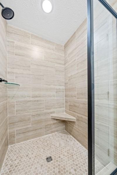 bathroom with a shower with door and a textured ceiling