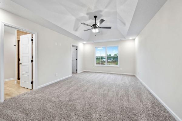 carpeted empty room featuring a tray ceiling and ceiling fan