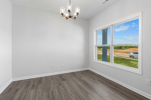 empty room with dark hardwood / wood-style floors and a chandelier