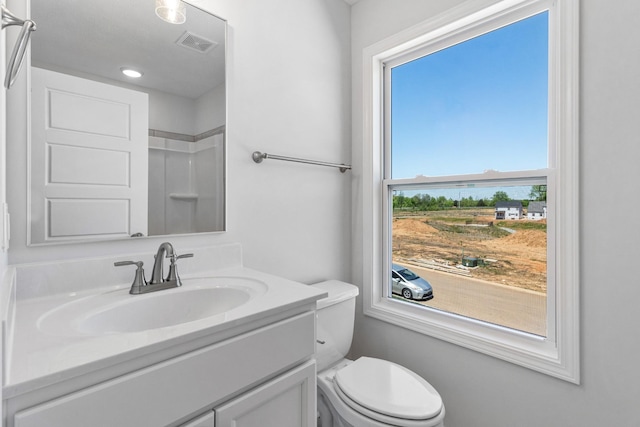 bathroom featuring vanity, walk in shower, and toilet