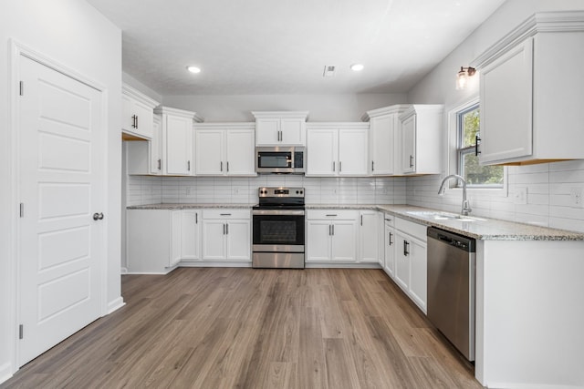 kitchen with light stone counters, sink, white cabinets, and appliances with stainless steel finishes