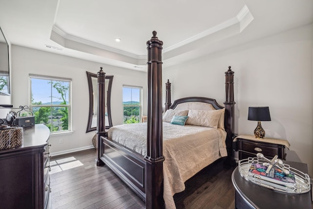 bedroom featuring crown molding, dark hardwood / wood-style flooring, and a tray ceiling