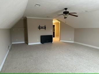 bonus room featuring vaulted ceiling, carpet flooring, a fireplace, and ceiling fan