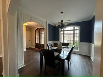 dining space with french doors, ornamental molding, dark wood-type flooring, and an inviting chandelier