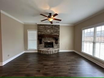 unfurnished living room featuring ornamental molding, dark hardwood / wood-style flooring, ceiling fan, and a fireplace