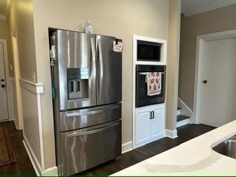 kitchen with dark hardwood / wood-style floors, black oven, built in microwave, ornamental molding, and stainless steel refrigerator with ice dispenser