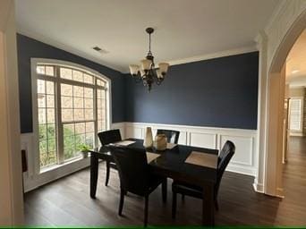 dining space with crown molding, wood-type flooring, and a notable chandelier