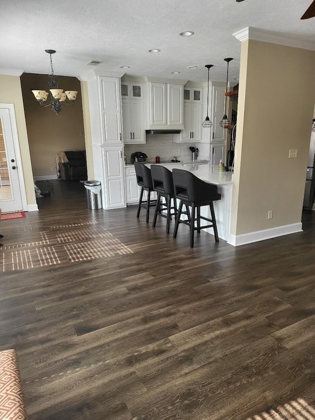 kitchen with pendant lighting, ornamental molding, dark hardwood / wood-style floors, and white cabinets