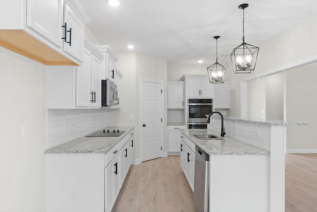 kitchen with white cabinetry, stainless steel appliances, sink, and hanging light fixtures