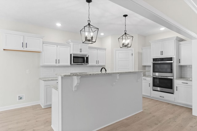 kitchen with white cabinetry, stainless steel appliances, and a center island with sink