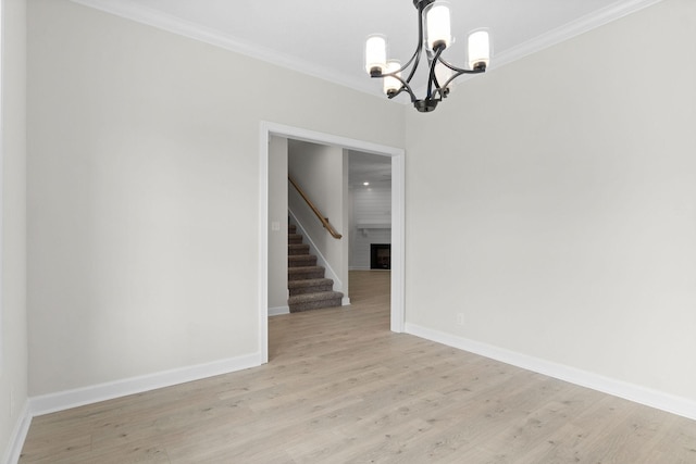 unfurnished room featuring a notable chandelier, crown molding, light hardwood / wood-style flooring, and a large fireplace