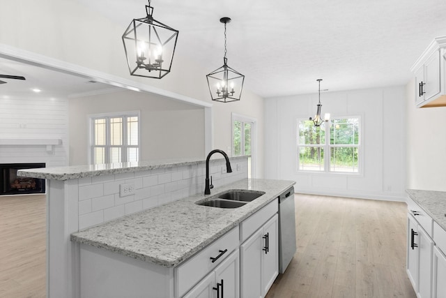 kitchen with white cabinetry, sink, stainless steel dishwasher, and hanging light fixtures