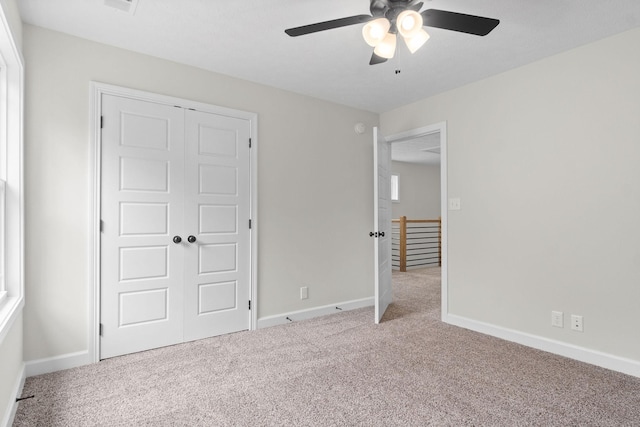 unfurnished bedroom featuring light carpet, ceiling fan, and a closet